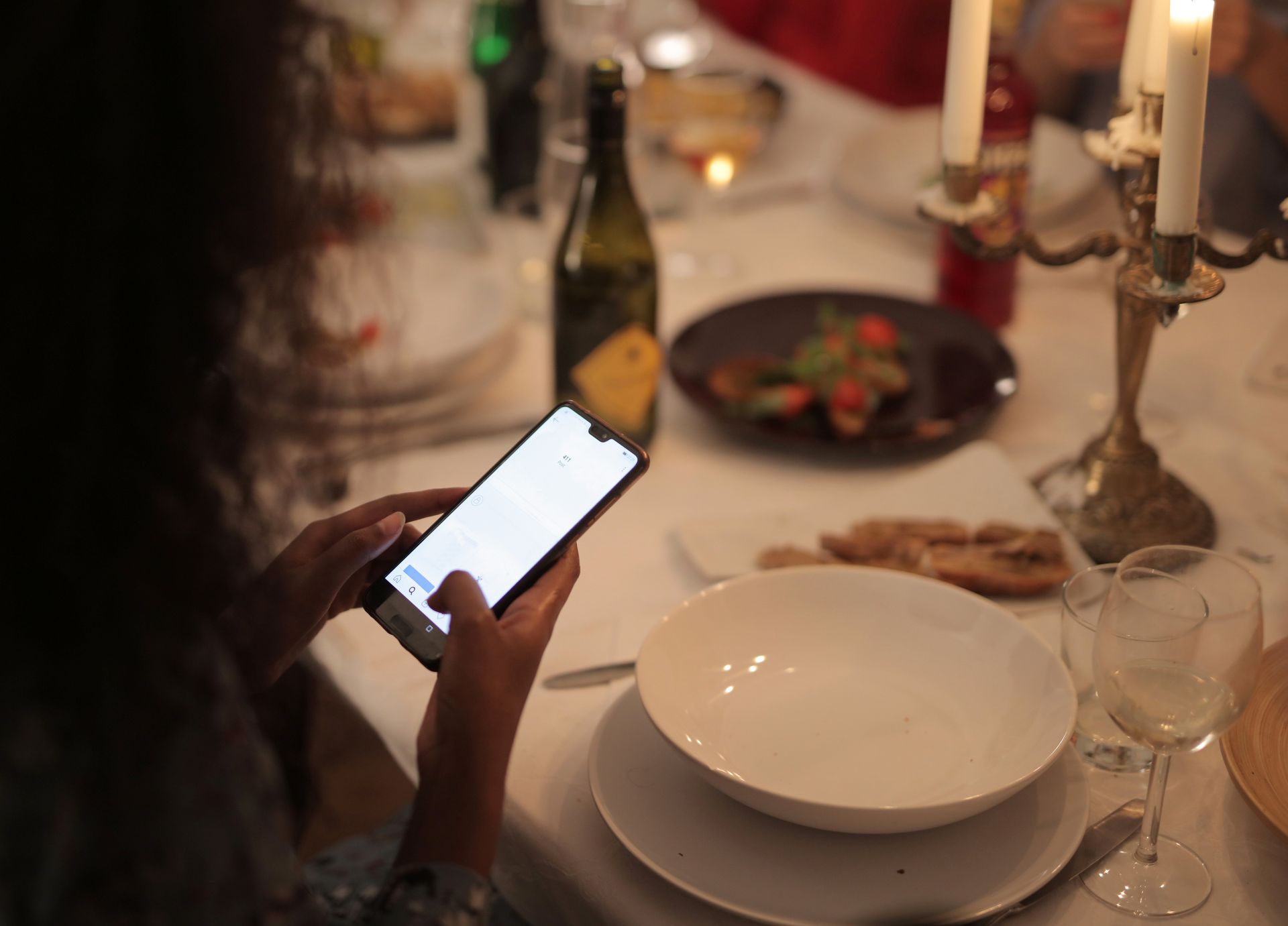 A customer ordering from their phone at a candlelit table