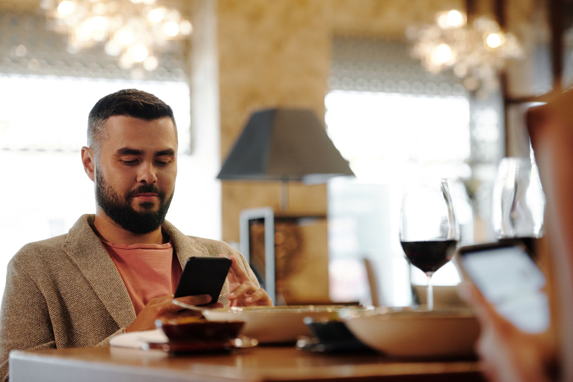A customer ordering from their phone over a glass of wine