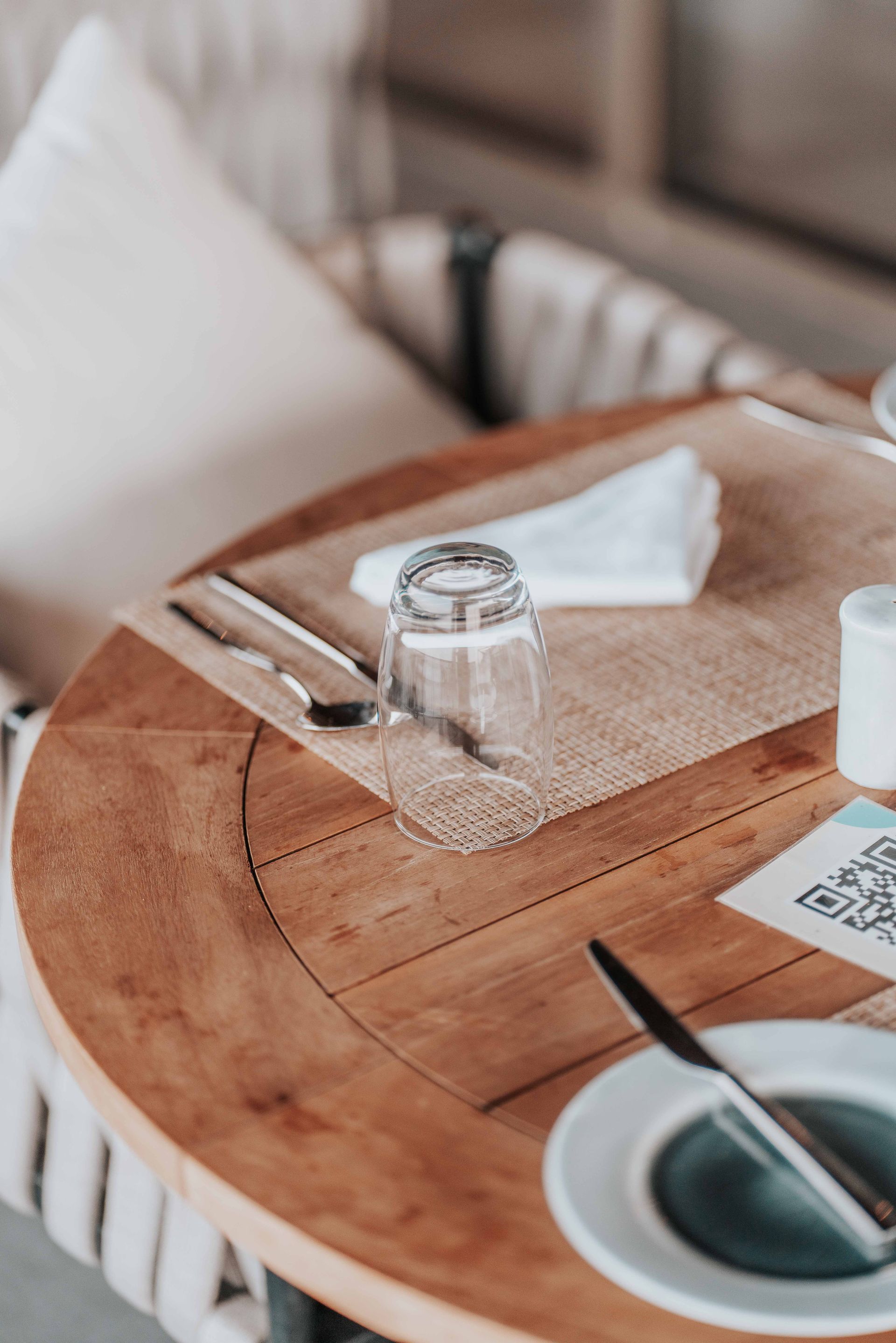 A restaurant table set with cutlery, a glass and a QR code menu card ready to scan